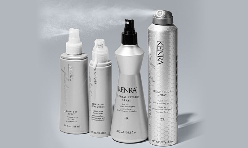 Four Kenra Professional heat-protection styling products — Blow-Dry Spray, Silkening Heat Creme, Thermal Styling Spray 19, and Heat Block Spray 22 — displayed in a row against a soft gray background with a fine mist visible above them. Featured image for 
