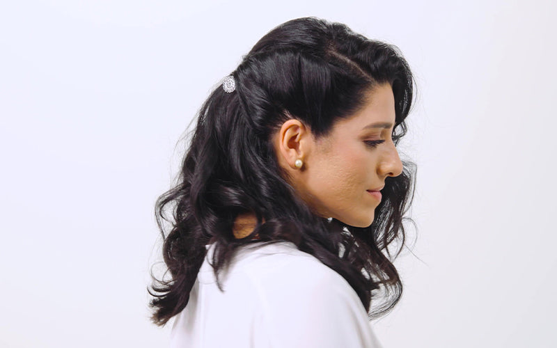 A woman shown in profile with a polished dark updo adorned with small decorative hair pins, wearing statement earrings against a white background. Featured image for blog post: Valentine’s Date Night Hairstyles
